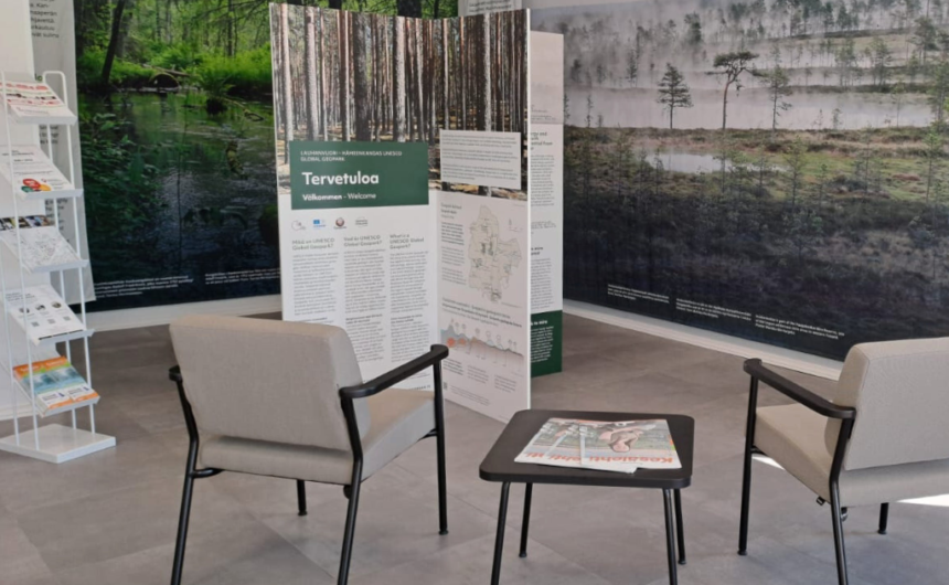 ylieskuva infopisteen tiloista, kuvassa esiteteline, kaksi tuolia, pieni pöytä ja taustalla isot kuvat geoparkista